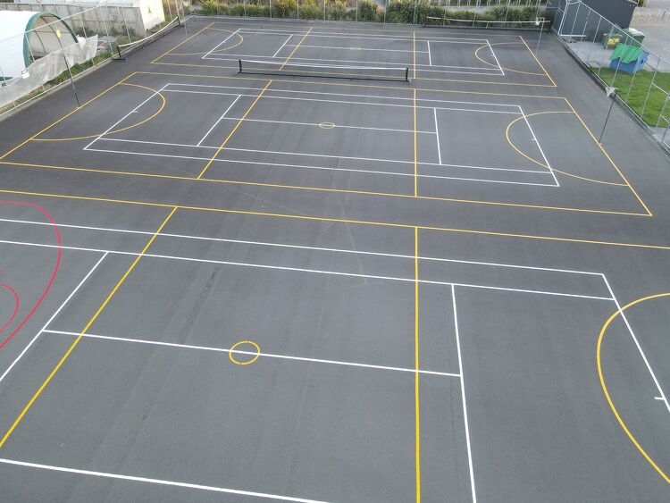 Multi-purpose sports courts featuring tennis, basketball, and netball markings with precise white and yellow lines.
