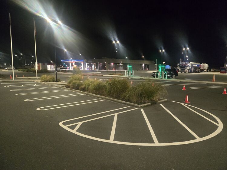 Newly marked car park with bright white lines and EV charging bays at night.