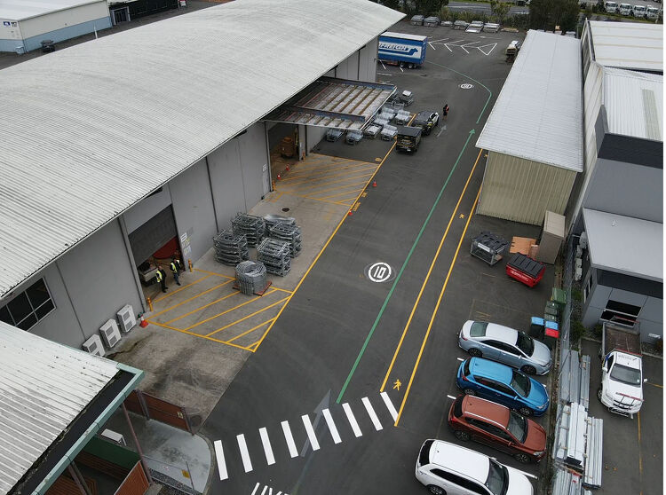 Aerial view of warehouse yard with clear yellow and green line markings, pedestrian crossings, and traffic flow indicators.