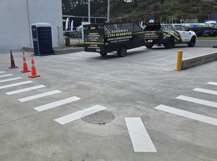 Accurate Linemarking vehicles parked beside freshly painted white pedestrian crossings on new concrete surface.