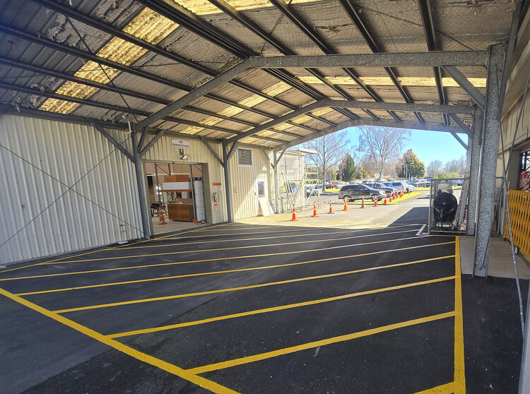 Covered loading bay area with newly applied yellow safety lines to manage vehicle and pedestrian zones.
