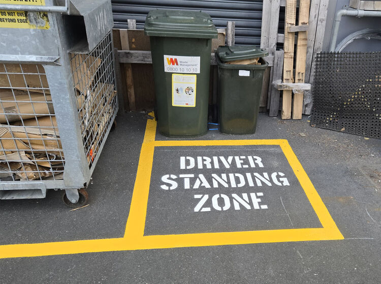 Designated “Driver Standing Zone” marked in yellow paint for safety near loading and waste areas.