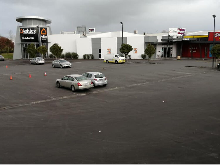 Large car park before line marking with minimal visible lines and scattered vehicles.