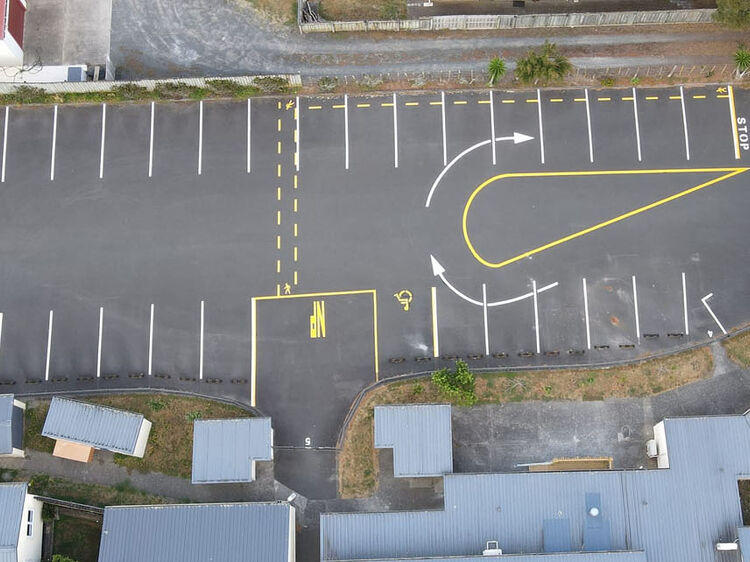 Aerial view of freshly marked car park with directional arrows and safety zones.