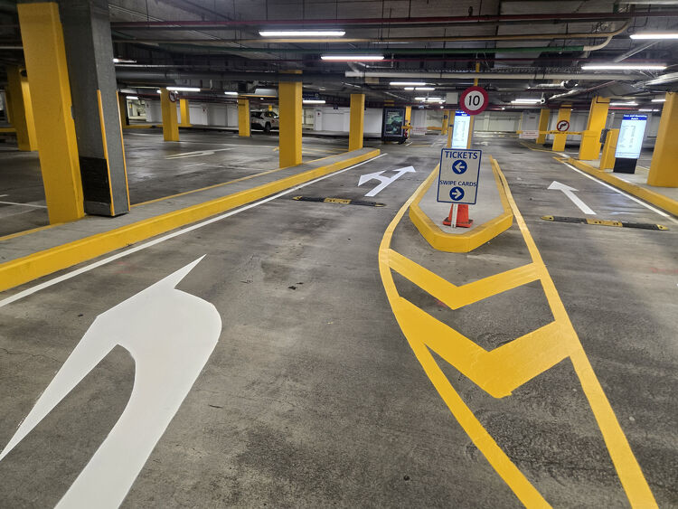 Underground parking area with clear white and yellow directional arrows and lane markings for smooth traffic flow.