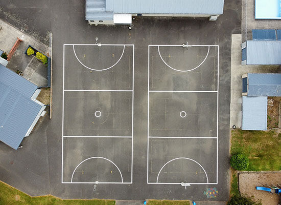 Aerial view of two full-sized netball courts with freshly painted white line markings by Accurate Linemarking.