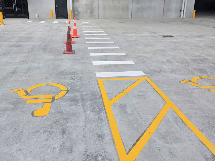 Accessible parking and pedestrian crossing markings with bright yellow and white paint for improved visibility.