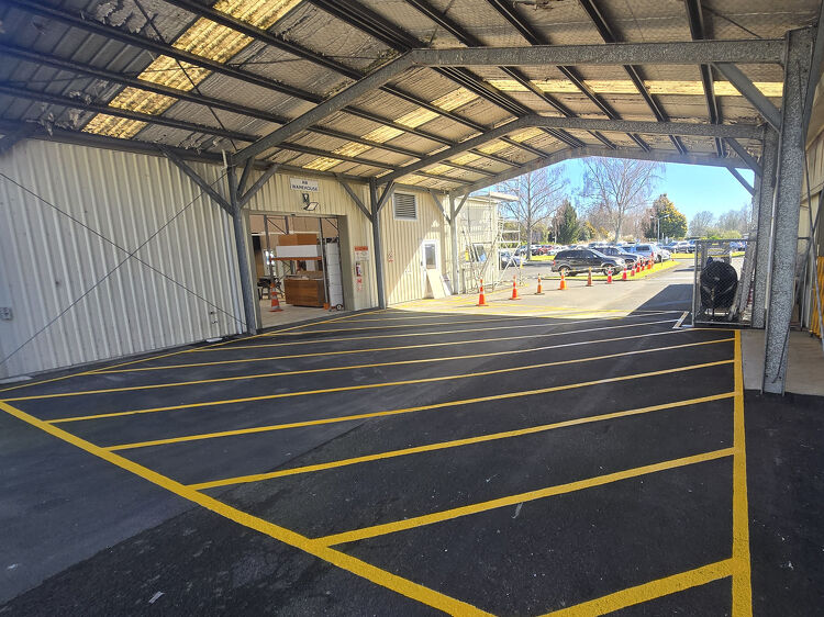 Freshly painted yellow line markings under a covered loading bay area to improve traffic flow and safety.
