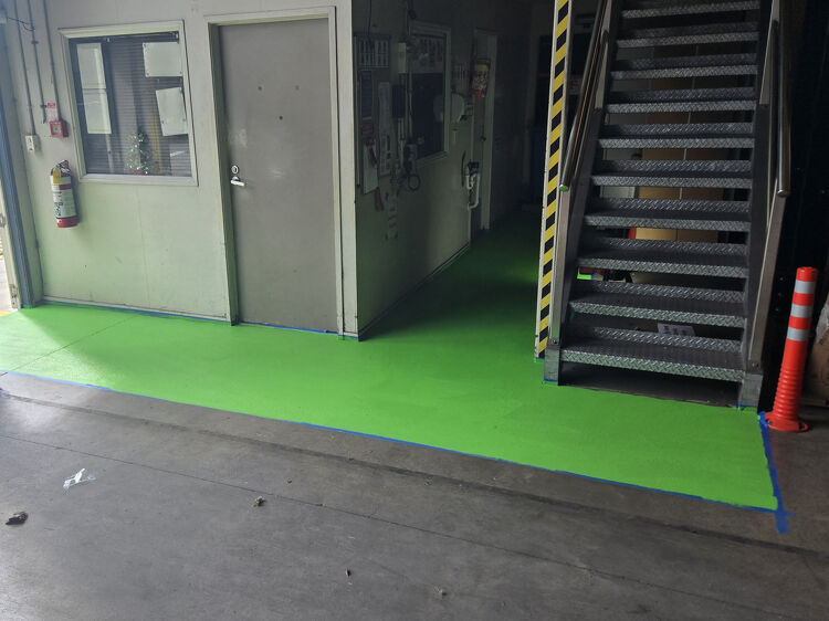 Green non-slip floor coating in industrial walkway for enhanced worker safety.