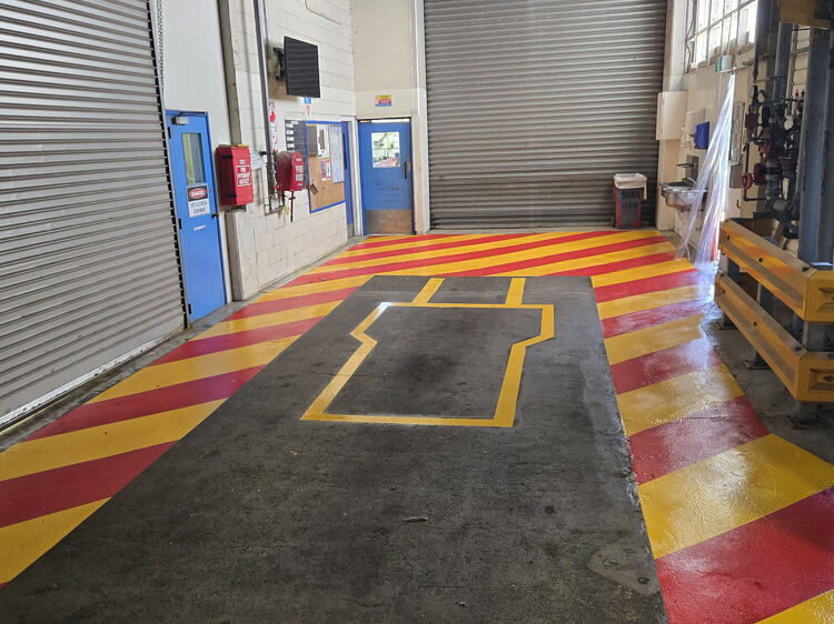 Workshop floor with red and yellow hazard zone markings for equipment safety clearance.