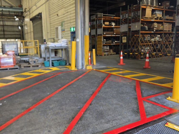 Warehouse entry area with clear red and yellow floor markings for traffic and pedestrian separation.